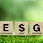 Wooden blocks with the letters E, S, and G, representing Environmental, Social, and Governance, on a grass background.